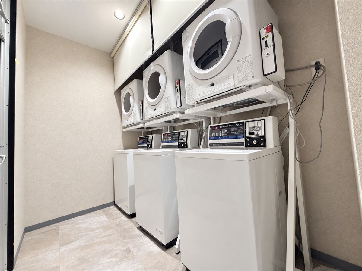 A laundry room with three front-loading washing machines and two dryers.