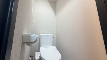 Een kleine, smalle badkamer met een wit toilet en een wandcloset.