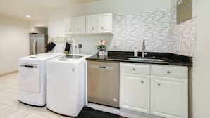 A modern kitchen with white cabinetry, a stainless steel refrigerator, a dishwasher, and a black countertop. - Gateway to DC, Waterfalls & More! McLean Apartment (McLean)