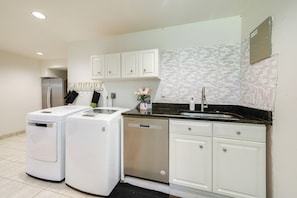 A modern kitchen with white cabinetry, a stainless steel refrigerator, a dishwasher, and a black countertop. - Gateway to DC, Waterfalls & More! McLean Apartment (McLean)