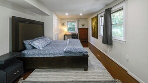A bedroom with a bed, bedside tables, a dresser, a window with curtains, and a painting on the wall. - Gateway to DC, Waterfalls & More! McLean Apartment (McLean)