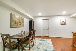 A dining area with a wooden table, chairs, a rug, and a painting on the wall. - McLean 2BR | 2 Kings | DC, Tysons & Great Falls (McLean)