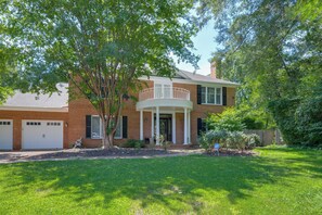A two-story house with a brick facade, a covered front porch, and a well-maintained lawn. - McLean 2BR | 2 Kings | DC, Tysons & Great Falls (McLean)