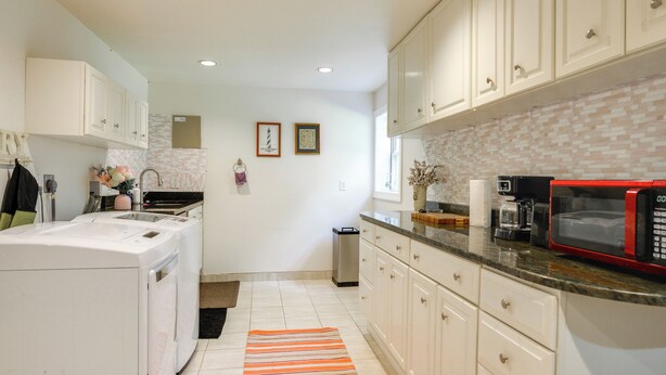 A kitchen with white cabinets, a red microwave, and a tiled backsplash. - Gateway to DC, Waterfalls & More! McLean Apartment (McLean)