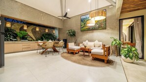 A modern living area with a sofa set, dining table, chairs, and a large painting on the wall. - Serene 2BR Retreat w Pool & Lounge, Canggu's Heart (Kuta Utara)