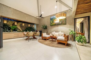 A modern living area with a sofa set, dining table, chairs, and a large painting on the wall. - Serene 2BR Retreat w Pool & Lounge, Canggu's Heart (Kuta Utara)
