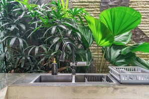 A kitchen sink with a faucet, a bottle, and a dish rack. - Serene 2BR Retreat w Pool & Lounge, Canggu's Heart (Kuta Utara)
