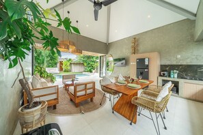 Un interior moderno con comedor, cocina y vistas a una piscina y jardín.