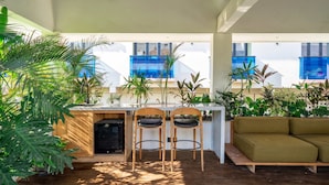Un área de estar al aire libre con una mesa y sillas, rodeada de exuberante follaje tropical.