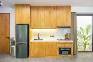 Eine moderne Küche mit Holzausstattung, einem Edelstahlkühlschrank, einer Spüle und einem Backofen.