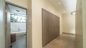 Um corredor com um guarda-roupa de madeira, uma banheira branca e uma cesta de vime.