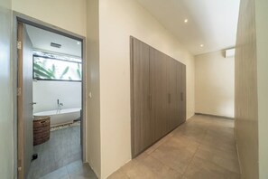 Ein Flur mit einem Holzschrank, einer weißen Badewanne und einem Korbwannenstuhl.