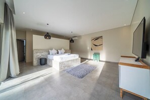 Ein modernes Schlafzimmer mit einem großen Bett, einem Fernseher und einer Wand mit Steinoptik.