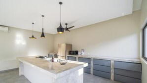 Uma cozinha moderna com ilha central, iluminação pendente e eletrodomésticos embutidos.