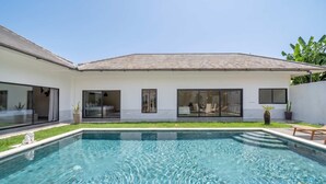 Uma casa moderna com piscina, janelas amplas e um gramado bem cuidado.