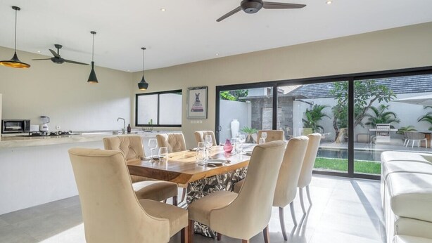 Uma área de jantar moderna com uma mesa grande, várias cadeiras e um ventilador de teto.