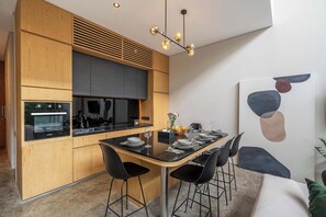 Une cuisine moderne avec des meubles en bois, un plan de travail noir et un coin repas avec une table dressée pour quatre personnes.