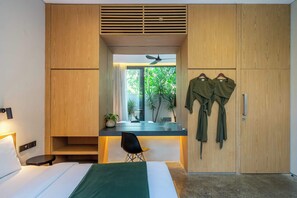 Une chambre à coucher comprenant un lit, une table de chevet, une chaise, une armoire et donnant sur un espace verdoyant.