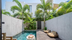 A pool with a floating table, surrounded by a wooden deck and a white wall. - Chic 3BR Townhouse • Beach Nearby • Pool • Umalas (Kuta Utara)