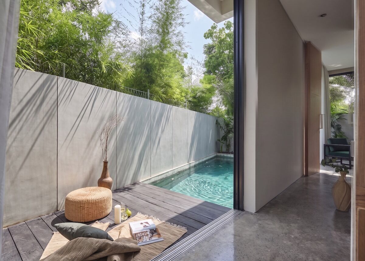 Ein modernes Interieur mit Pool, einer Holzterrasse und Blick auf die grüne Umgebung.