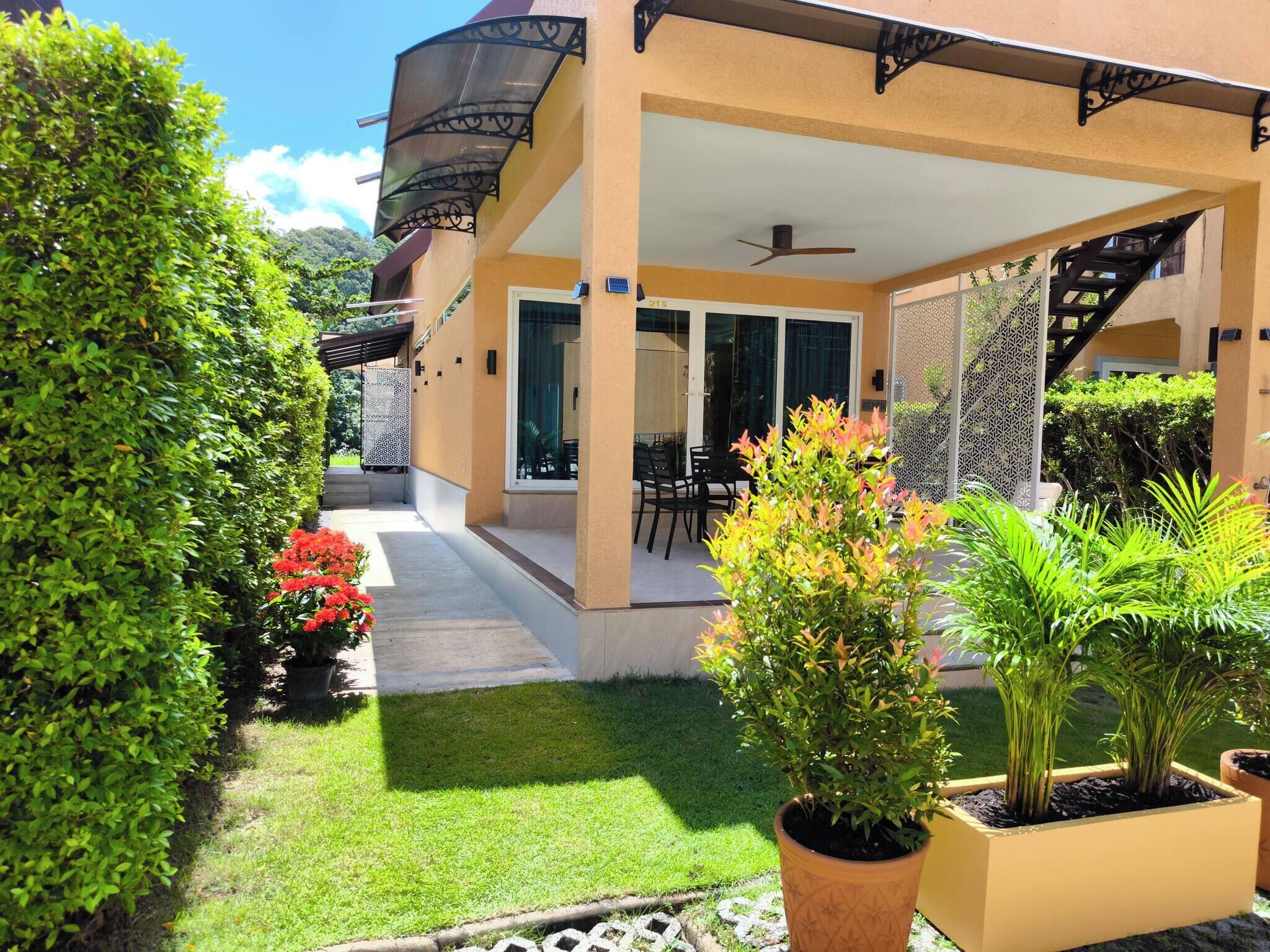A covered outdoor patio with a dining area, a staircase, and potted plants.