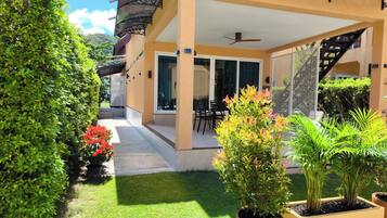 A covered outdoor patio with a dining area, a staircase, and potted plants.