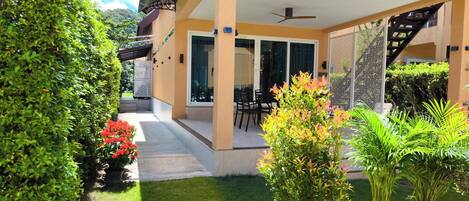 A covered outdoor patio with a dining area, a staircase, and potted plants.