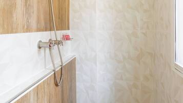 A shower with a wooden panel design, a white tiled wall with a geometric pattern, and a wooden floor.