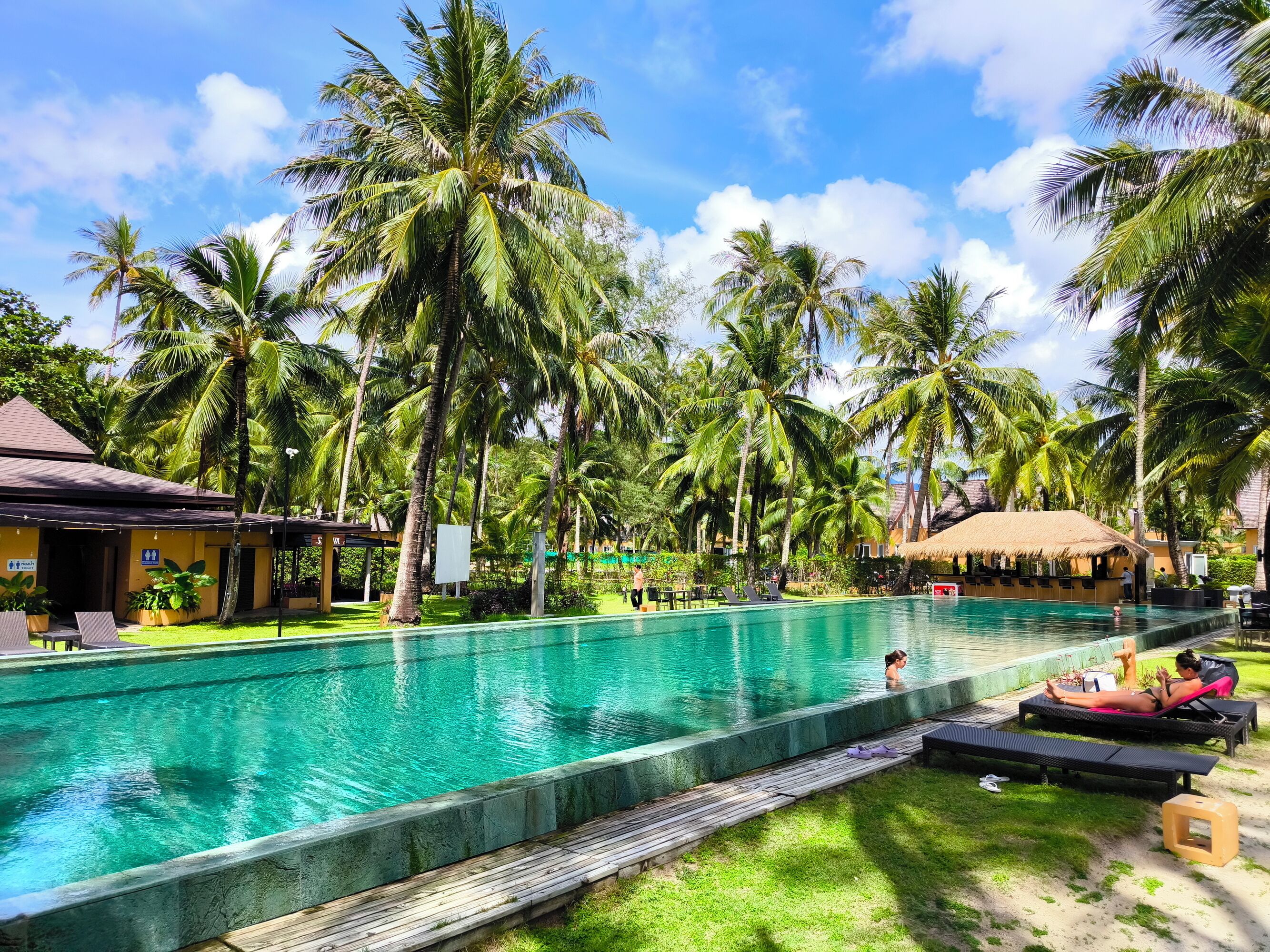 A pool area with lounge chairs and a thatched-roof structure.