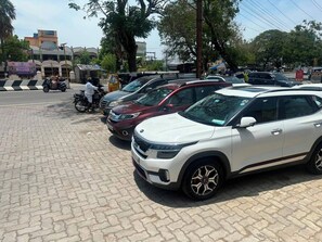 Un área de estacionamiento con varios vehículos, incluyendo un SUV blanco y un coche rojo.