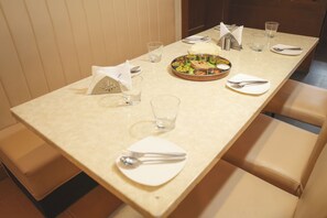 A dining table set with plates, cutlery, glasses, and a central dish. - Hotel Himalayaa (Tiruvannamalai)