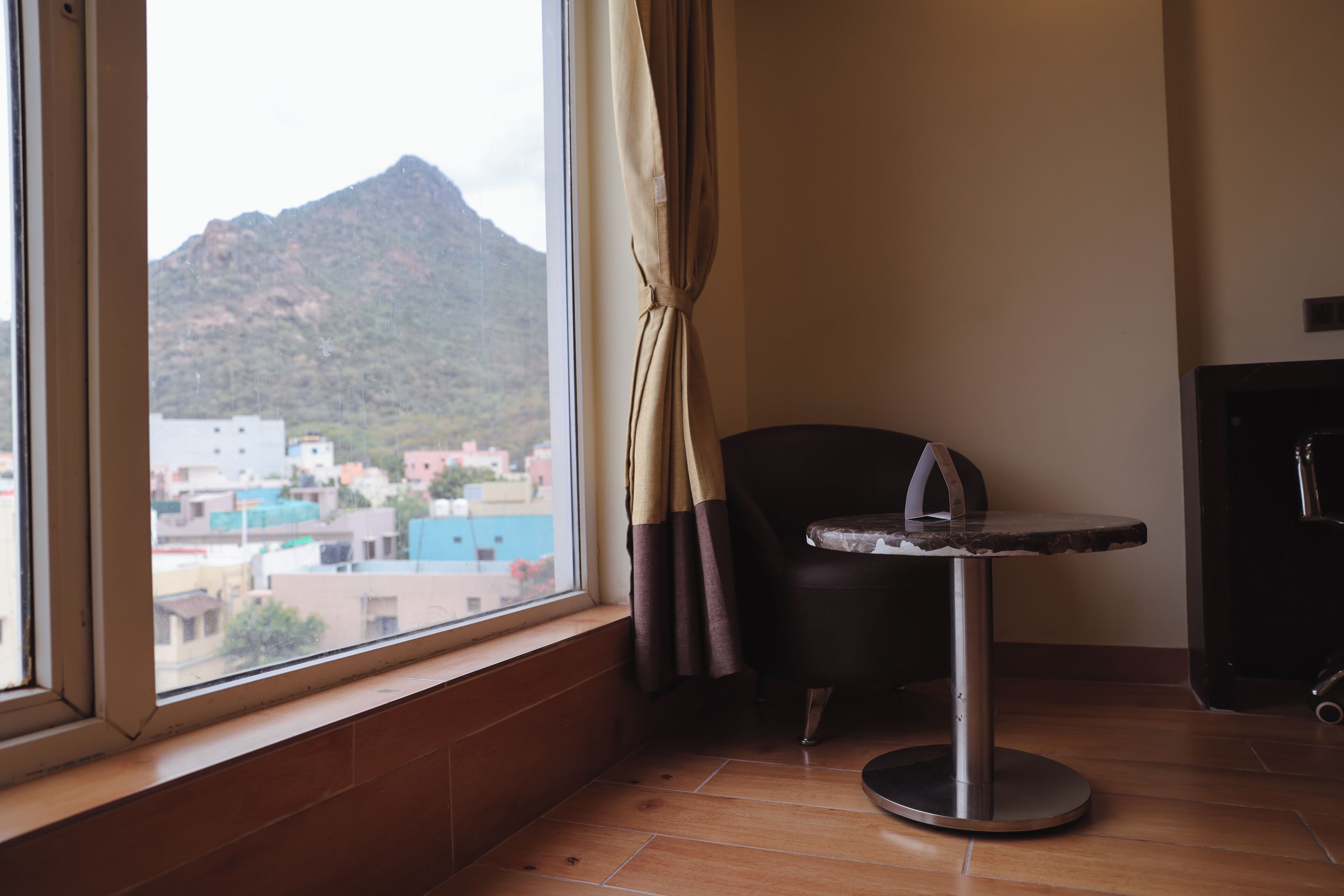Ein Zimmer mit Blick auf einen Berg, ein Sessel, ein kleiner Tisch und ein Schrank.