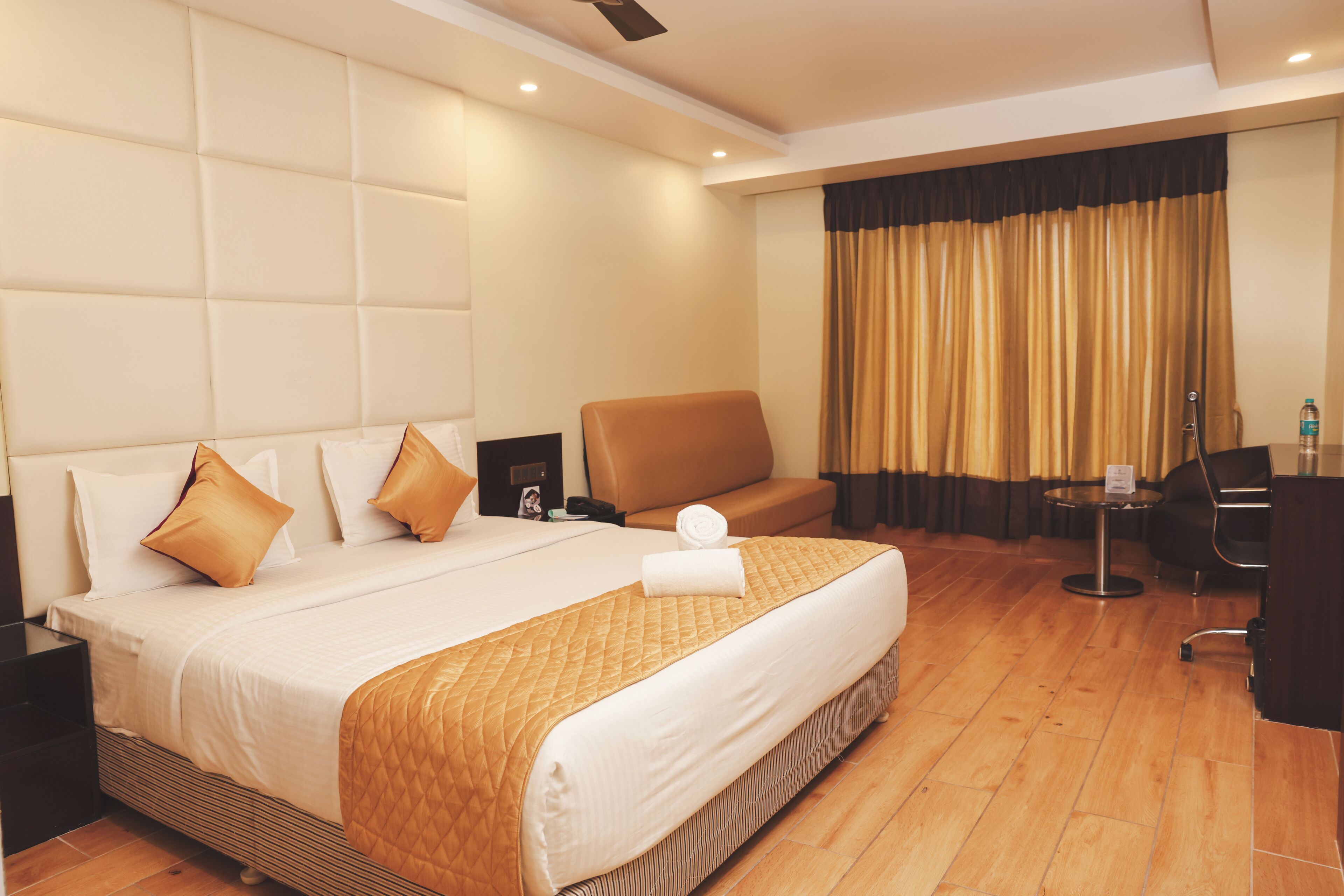 A hotel room with a large bed, a sofa, a desk, and a chair.