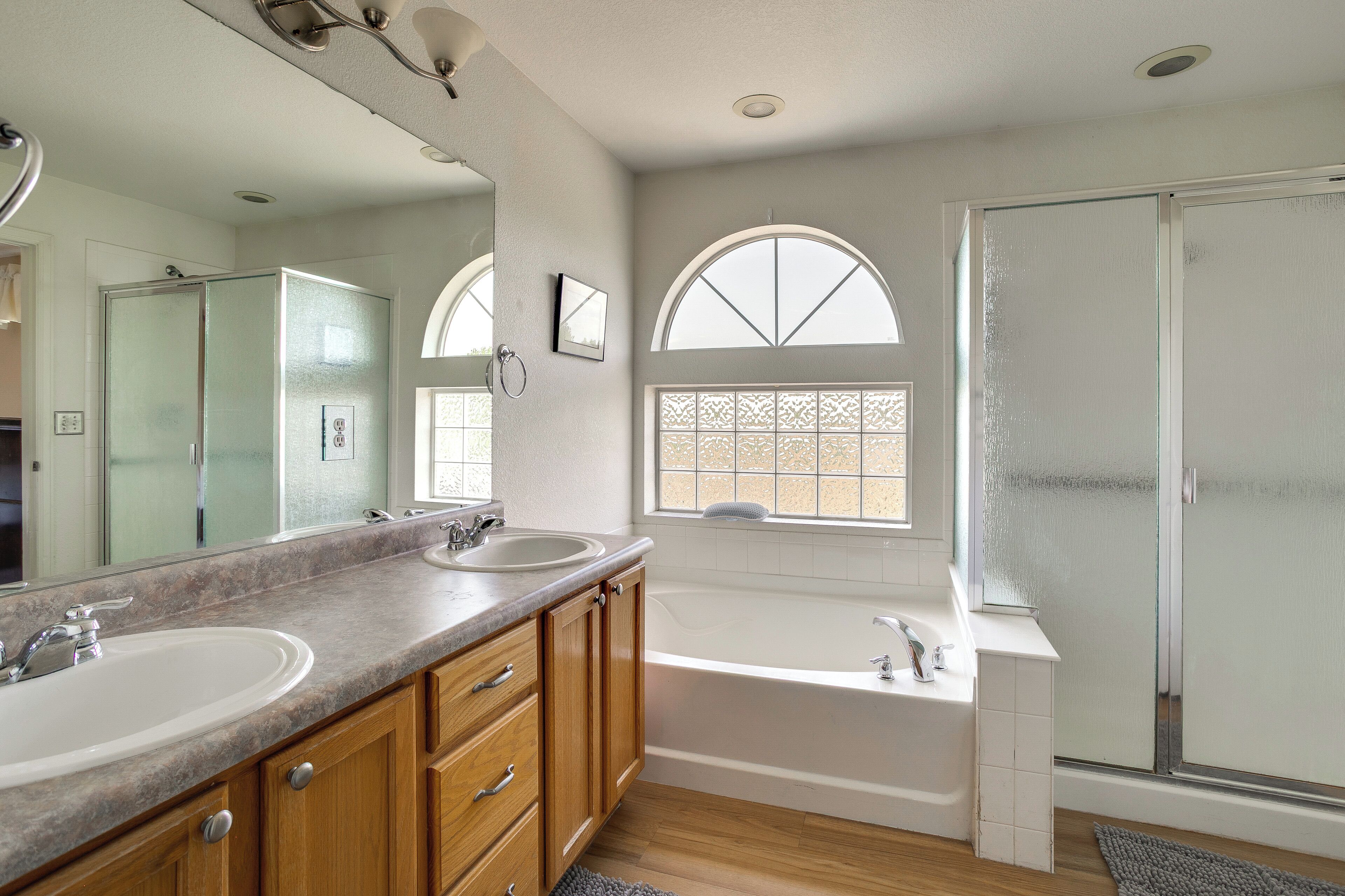 A bathroom with two sinks, a bathtub, a shower, and a large mirror.