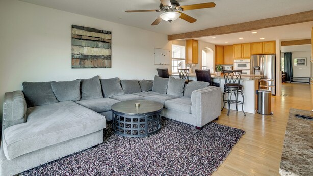 A modern living room with a sectional sofa, a coffee table, and a ceiling fan. - Fenced Yard! Family Home on Golf Course in Denver (Denver)