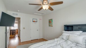 A bedroom with a bed, a ceiling fan, a wall-mounted TV, a door with a basketball hoop, and a painting. - Fenced Yard! Family Home on Golf Course in Denver (Denver)