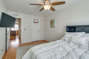 Ein Schlafzimmer mit einem Bett, einem Deckenventilator, einem an der Wand montierten Fernseher, einer Tür mit Basketballkorb und einem Gemälde.
