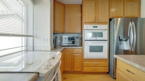 A kitchen with wooden cabinets, a stainless steel refrigerator, a microwave, an oven, and a stovetop. - Fenced Yard! Family Home on Golf Course in Denver (Denver)