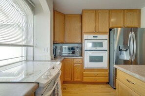 A kitchen with wooden cabinets, a stainless steel refrigerator, a microwave, an oven, and a stovetop.