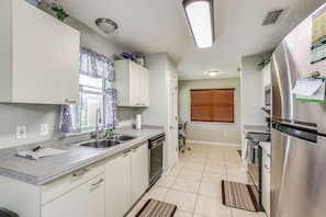 A modern kitchen with a stainless steel refrigerator, a built-in dishwasher, and a granite countertop. - 'Fifth Gold Tee' Fairway Views, Lanai & Golf Cart! (Lady Lake)