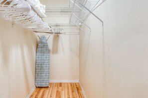 A narrow hallway with a wooden floor, a white wall, and a metal drying rack with clothes. - 'Fifth Gold Tee' Fairway Views, Lanai & Golf Cart! (Lady Lake)