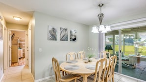Un coin repas avec une table ronde, six chaises et une plante en pot.