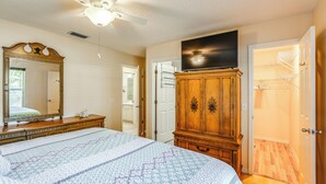 Une chambre à coucher avec un grand lit, une armoire, un ventilateur de plafond et un téléviseur.