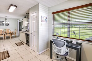 A modern kitchen with a dining area, a computer desk with a chair, and a window with blinds. - 'Fifth Gold Tee' Fairway Views, Lanai & Golf Cart! (Lady Lake)