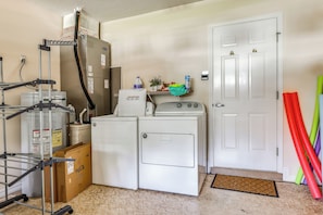 A laundry room with a washer, dryer, and stacked cardboard boxes. - 'Fifth Gold Tee' Fairway Views, Lanai & Golf Cart! (Lady Lake)