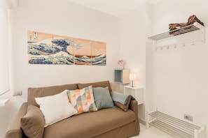 A modern living room with a brown sofa, a wall-mounted artwork, a side table with a lamp, and a built-in towel rack. - [ViaVeneto333]ModernApartment-FreeParking (La Spezia)