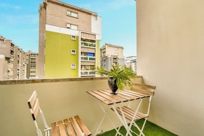 A balcony with a wooden table and chairs, a potted plant, and a view of surrounding buildings. - [ViaVeneto333]ModernApartment-FreeParking (La Spezia)