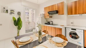Une cuisine moderne avec des meubles en bois, un four à micro-ondes encastré et un lave-linge.