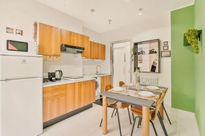 A compact kitchen with wooden cabinets, a microwave, and a dining area with a table set for two. - [ViaVeneto333]ModernApartment-FreeParking (La Spezia)