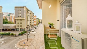 Un balcon avec une petite table et des chaises, un pot de fleurs et un appareil de climatisation Daikin.